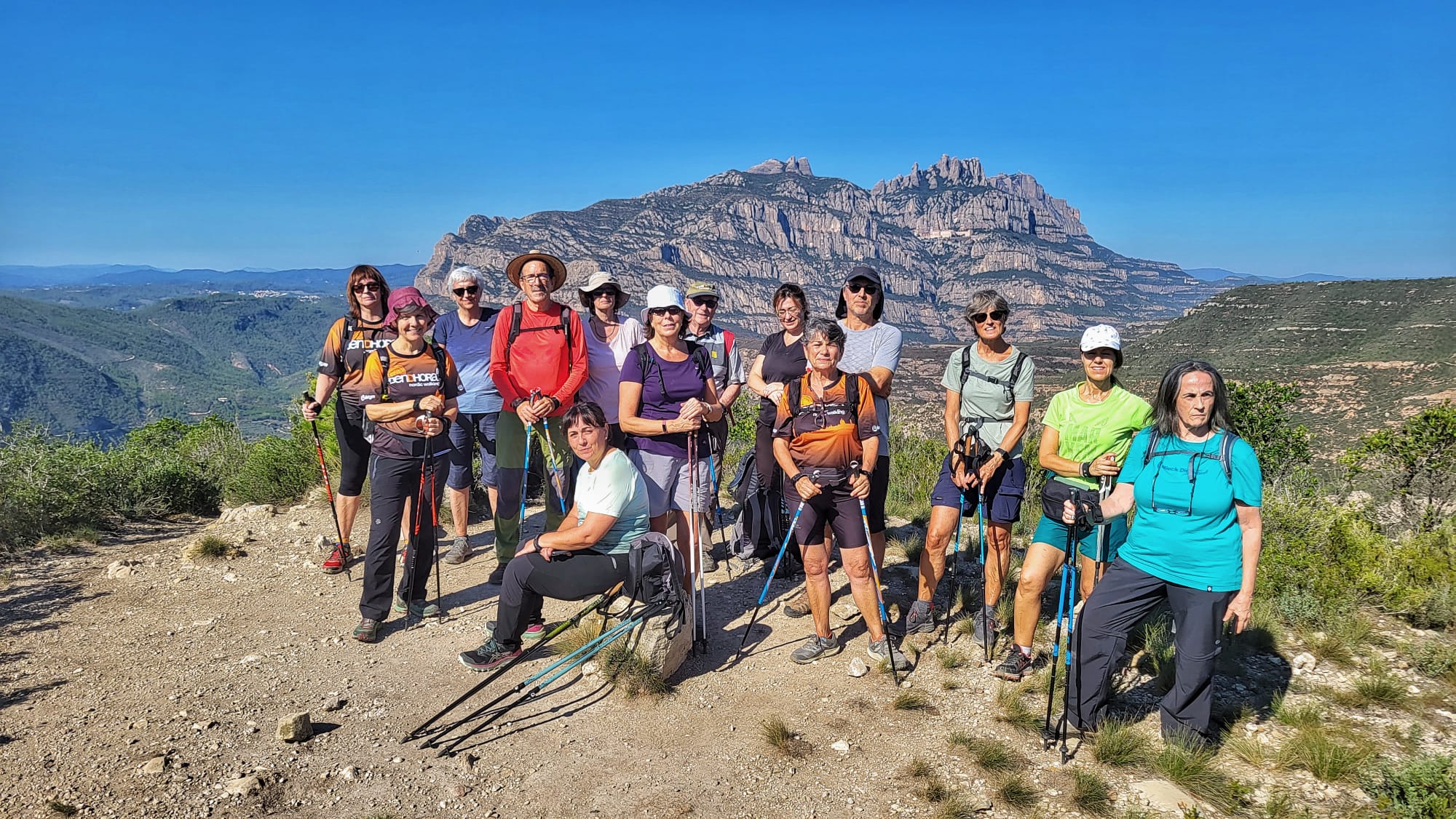 Grup de persones al Puig Cendrós amb Montserrat de fons